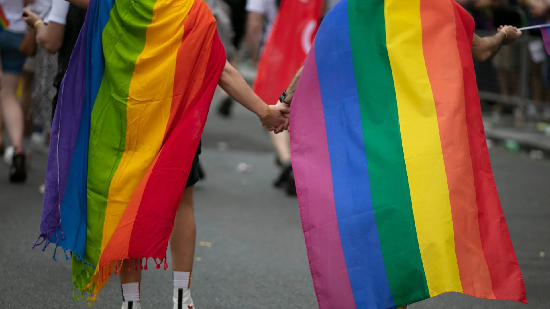 Couple in Rainbow Cape Walking at a Pride Parade